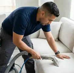 Professional upholstery cleaning technician using an extraction wand to deep-clean a fabric sofa, Henderson, NV.