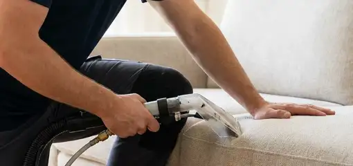 Professional upholstery cleaner deep-cleaning a fabric sofa with a handheld extraction tool, Henderson, NV.